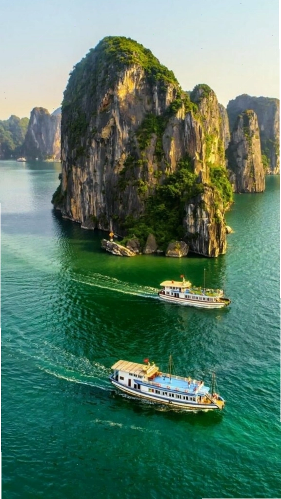 Du thuyền nhỏ giữa vịnh biển xanh và núi đá