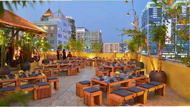 Không gian cafe sân thượng với nội thất gỗ ấm cúng và cây xanh mát mẻ